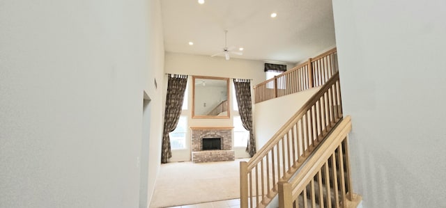 stairs with carpet, a fireplace, recessed lighting, a towering ceiling, and a ceiling fan