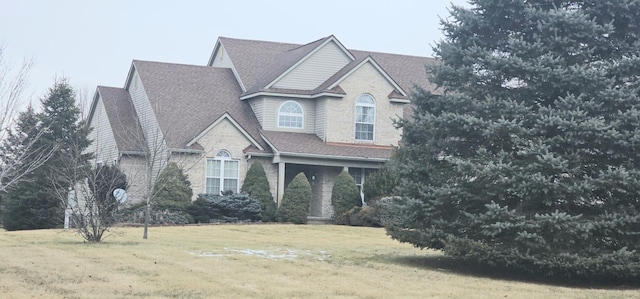 view of front of property with roof with shingles and a front yard