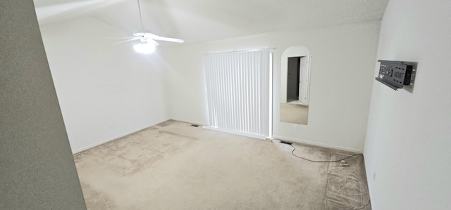 unfurnished room featuring ceiling fan, arched walkways, and light colored carpet