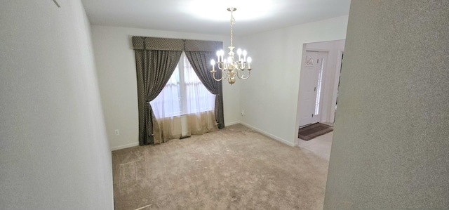 carpeted spare room featuring baseboards and a notable chandelier