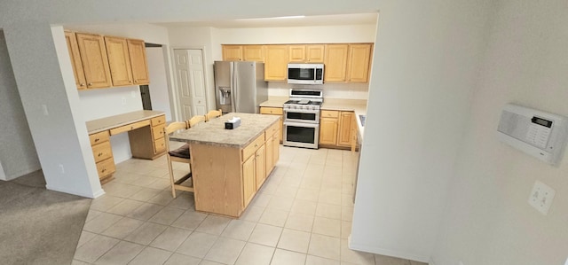 kitchen featuring a kitchen island, appliances with stainless steel finishes, a breakfast bar area, light countertops, and light brown cabinets