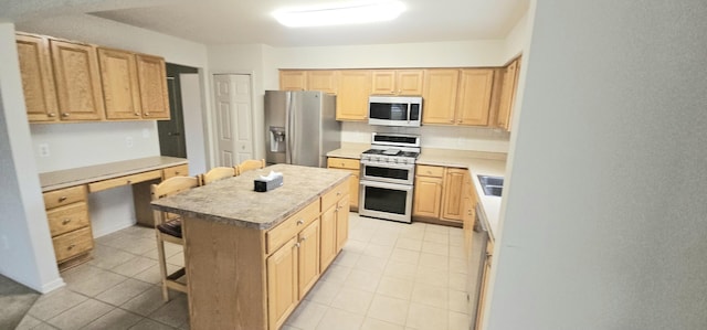 kitchen with a kitchen breakfast bar, light countertops, appliances with stainless steel finishes, a center island, and light brown cabinetry