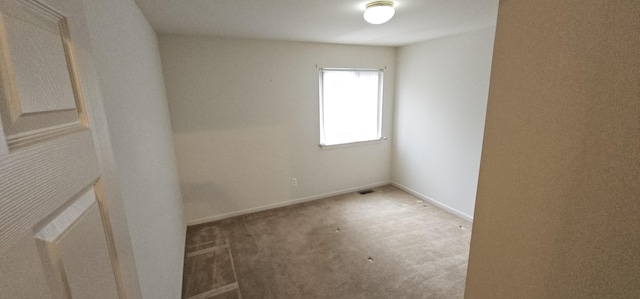unfurnished room with carpet, visible vents, and baseboards