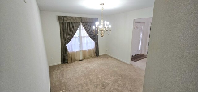 carpeted empty room with baseboards and an inviting chandelier