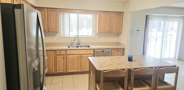 kitchen with a sink, light countertops, appliances with stainless steel finishes, tasteful backsplash, and brown cabinetry