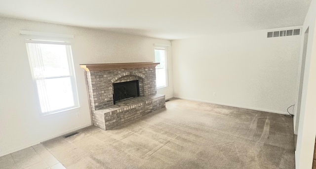 unfurnished living room featuring a brick fireplace, carpet flooring, visible vents, and baseboards