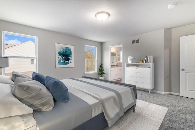 bedroom with light carpet, baseboards, visible vents, and ensuite bathroom