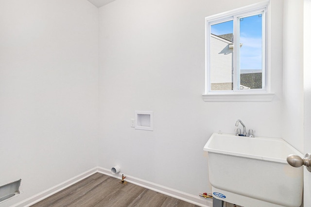 clothes washing area featuring hookup for a washing machine, hookup for a gas dryer, wood finished floors, laundry area, and baseboards