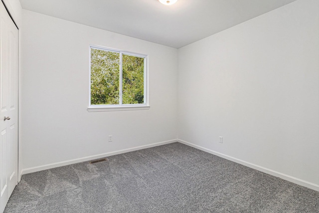 carpeted spare room featuring visible vents and baseboards