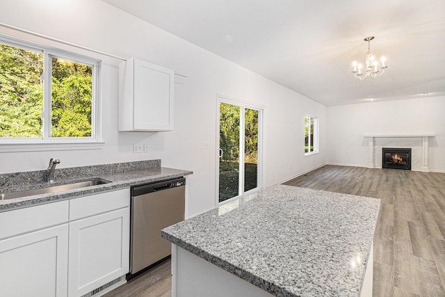 kitchen featuring a center island, decorative light fixtures, white cabinets, a sink, and dishwasher