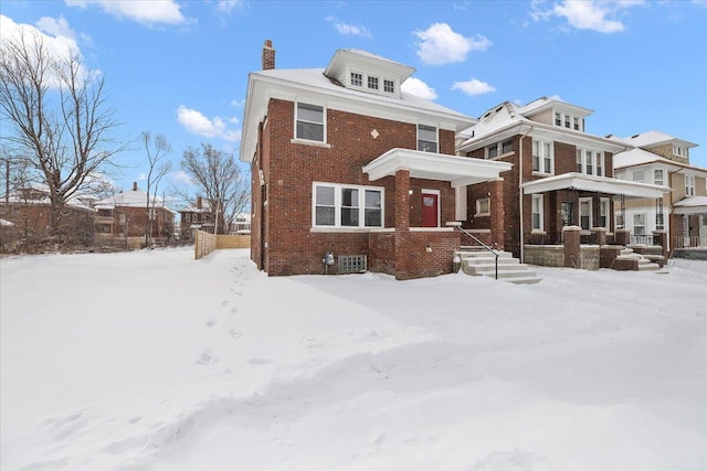 view of front facade featuring brick siding and a chimney