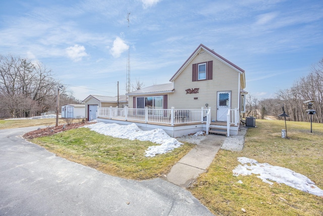 view of front of property featuring metal roof, a deck, an outdoor structure, central air condition unit, and a front yard