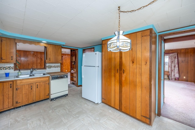 kitchen featuring white appliances, brown cabinets, a sink, and light colored carpet