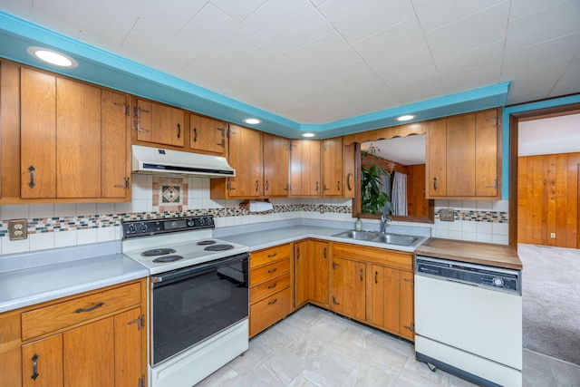 kitchen with under cabinet range hood, white appliances, a sink, light countertops, and brown cabinetry