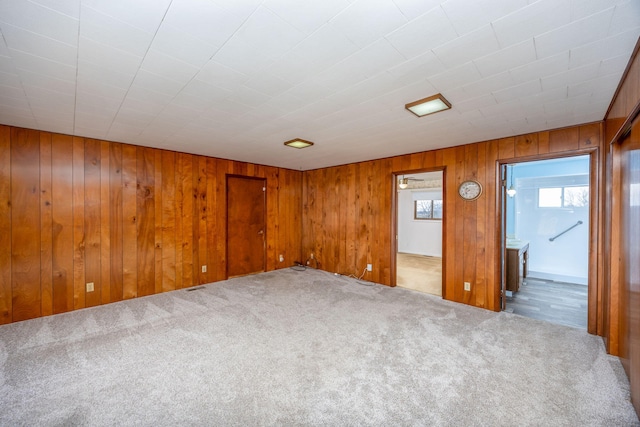 carpeted spare room with wooden walls