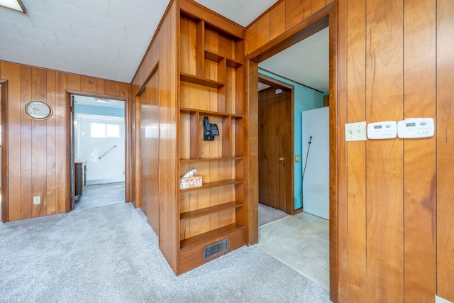 corridor with carpet, visible vents, and wood walls