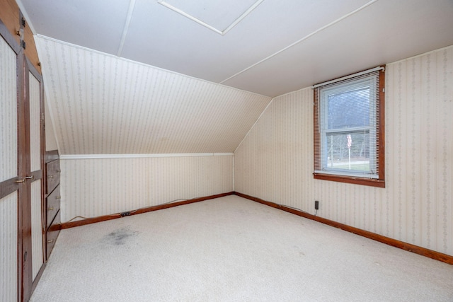 additional living space with vaulted ceiling, carpet floors, baseboards, and wallpapered walls