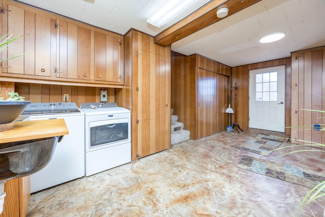 laundry area with wooden walls, cabinet space, and washer and dryer