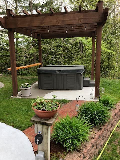 view of yard with a hot tub and a pergola