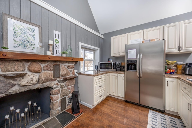 kitchen featuring lofted ceiling, stainless steel appliances, a fireplace, light stone countertops, and dark wood finished floors