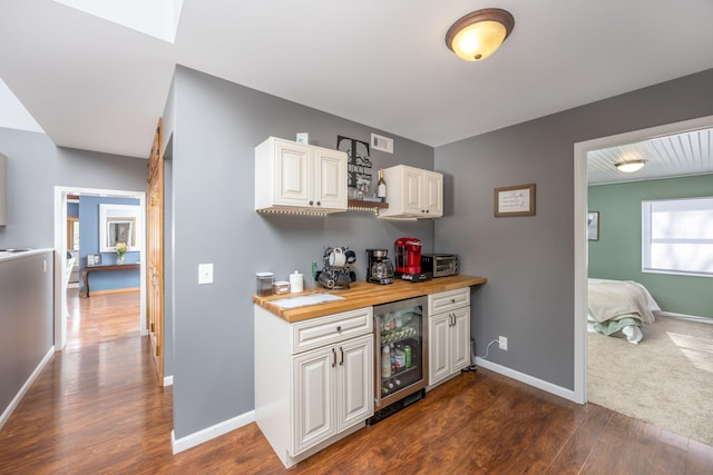 bar featuring dark wood-style floors, beverage cooler, and baseboards