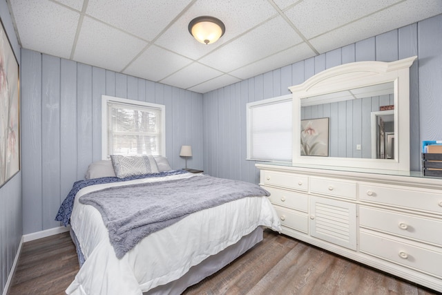 bedroom with a paneled ceiling and dark wood-style flooring