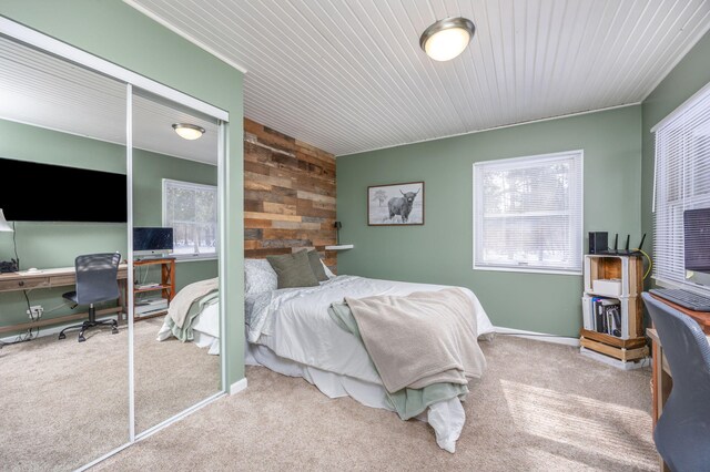 carpeted bedroom with wood walls, multiple windows, and baseboards