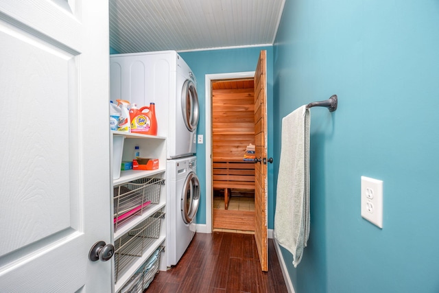 clothes washing area with laundry area, dark wood-style flooring, stacked washer and clothes dryer, and baseboards