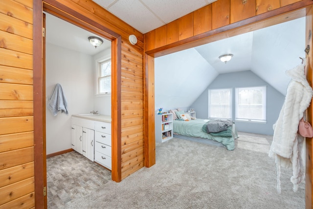 carpeted bedroom featuring lofted ceiling and a sink