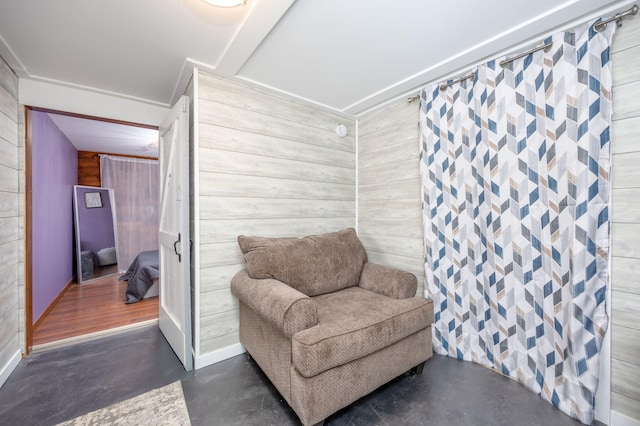 living area with wood walls and finished concrete floors