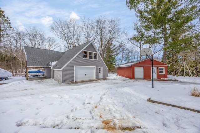 snow covered property with a garage and an outdoor structure