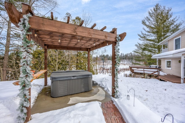 yard covered in snow with a hot tub, a wooden deck, and a pergola