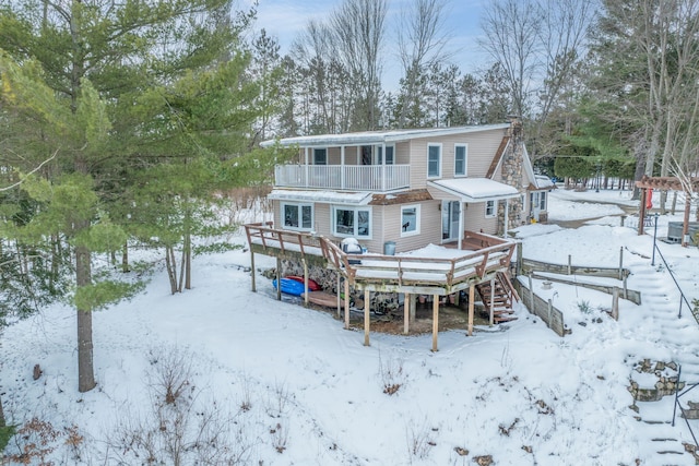 snow covered back of property featuring a balcony