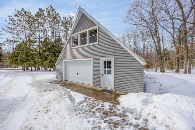 snow covered garage with a detached garage