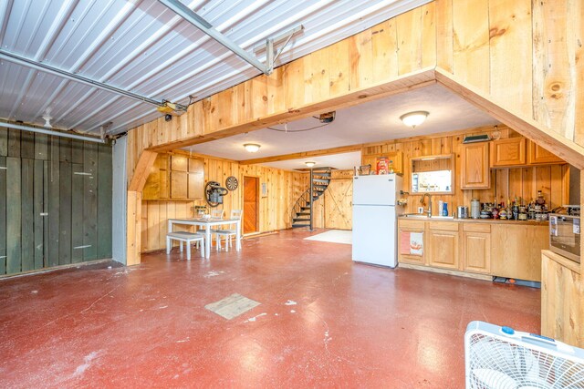 garage with a sink, freestanding refrigerator, and wooden walls