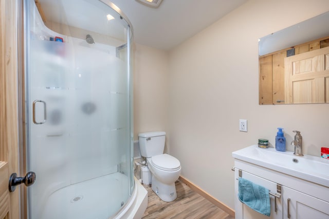 bathroom with a stall shower, baseboards, toilet, wood finished floors, and vanity