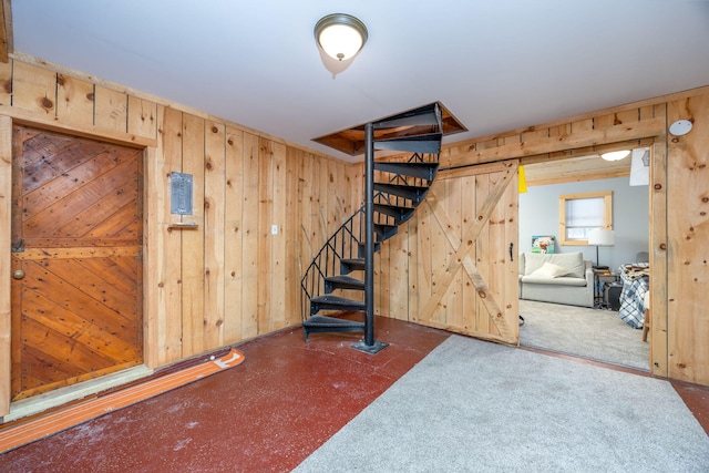 finished basement featuring a barn door, wood walls, and stairs