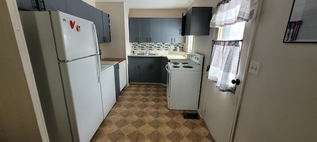 kitchen featuring white appliances, light countertops, a sink, and backsplash