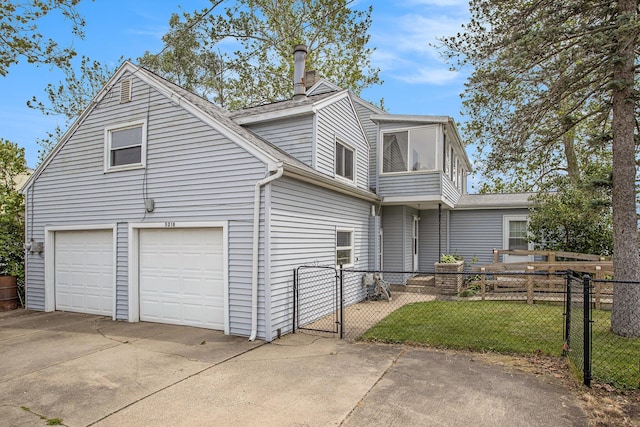 view of front of home with concrete driveway, a front yard, fence, and a gate