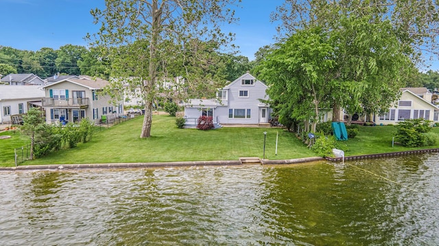 rear view of property with a yard, a water view, a residential view, and a balcony