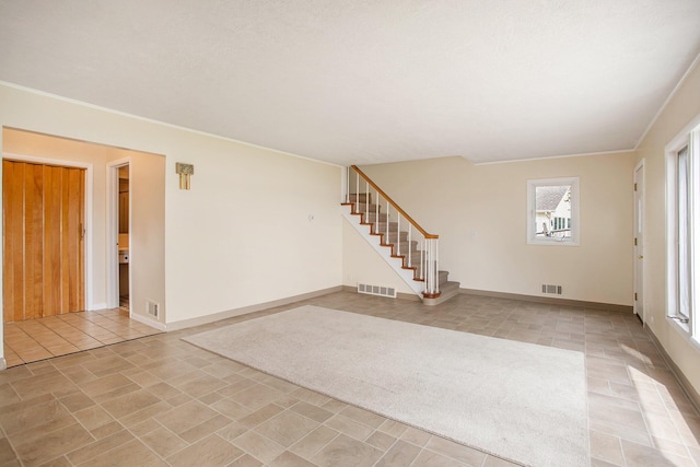 empty room with stairs, visible vents, and baseboards