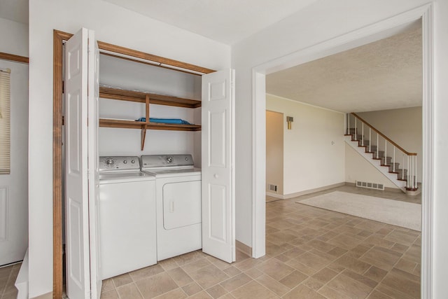 laundry area featuring washer and clothes dryer, visible vents, a textured ceiling, laundry area, and baseboards