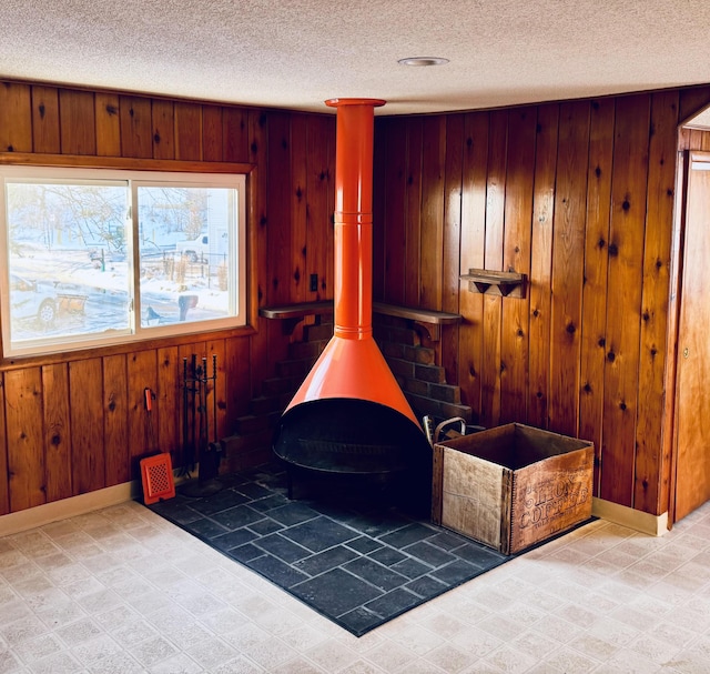 room details featuring a wood stove, wood walls, baseboards, and tile patterned floors