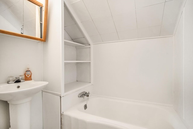 bathroom with a tub to relax in, lofted ceiling, and a sink