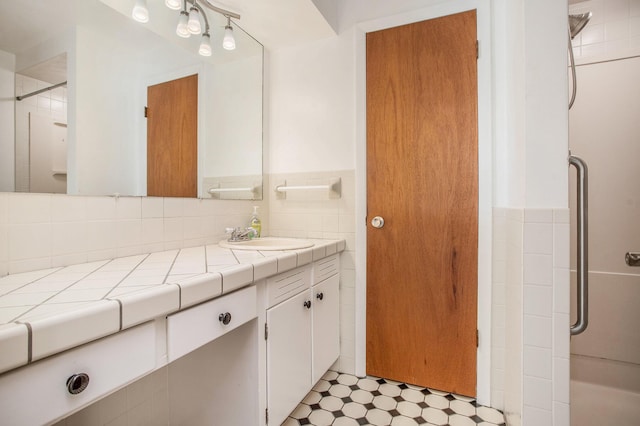 bathroom featuring vanity, a shower, tile walls, and tile patterned floors