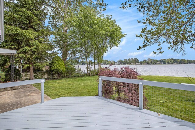 deck featuring a water view, fence, and a lawn