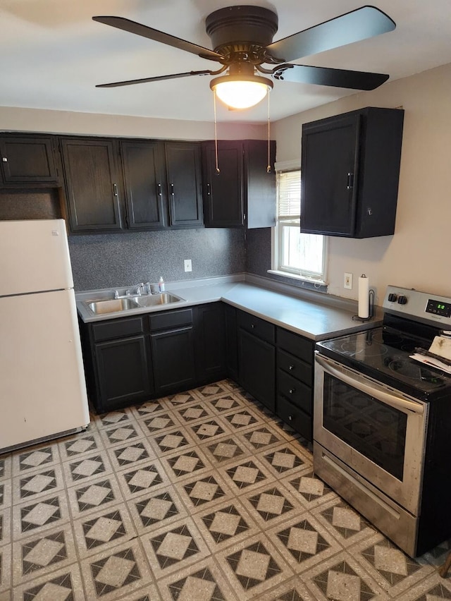 kitchen with decorative backsplash, freestanding refrigerator, a sink, ceiling fan, and stainless steel range with electric stovetop