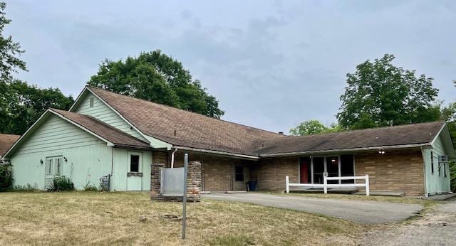 single story home with stone siding, a front lawn, and aphalt driveway