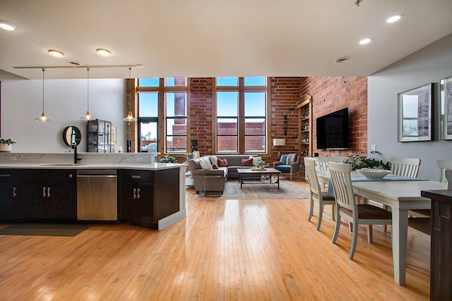 kitchen featuring light countertops, hanging light fixtures, open floor plan, a sink, and dishwasher