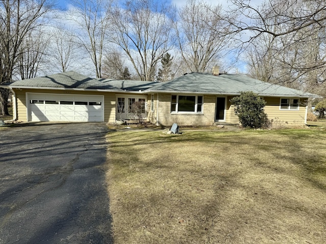 single story home with a garage, driveway, a front lawn, and a chimney